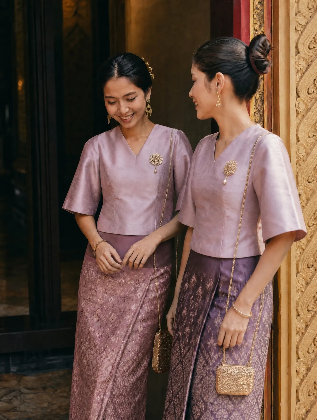 Two women wearing covered Thai blouses and skirts